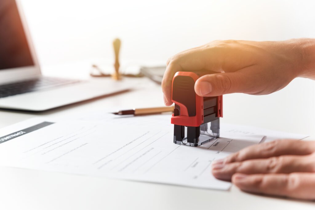 Notary public applying an official seal and signature to a legal document.